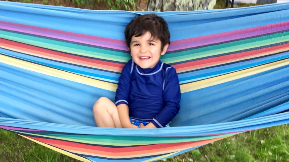A small boy in a rainbow hammock