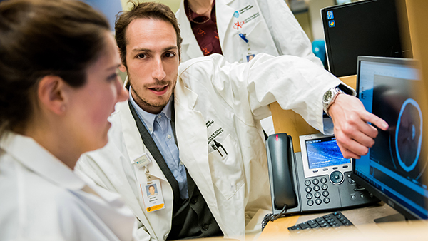Two providers discuss a medical scan on a screen.