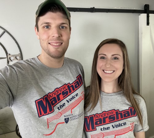 A smiling young man and woman with their arms around each other pose in T-shirts that read, "Andrew Marshall: The Voice."