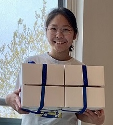 Erin Kim smiles while standing with boxes in her hands