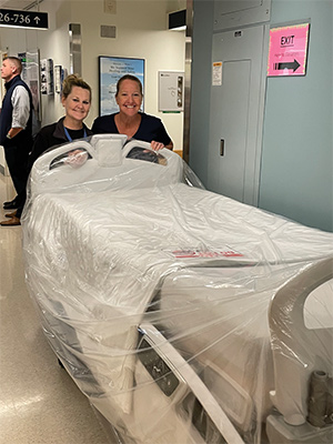 Two staff members moving a new inpatient bed