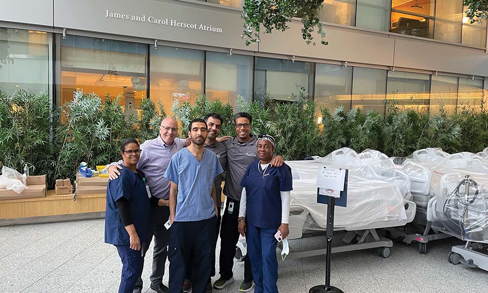 Six staff members standing outside a building with new inpatient beds and mattresses Six staff members standing outside a building with new inpatient beds and mattresses