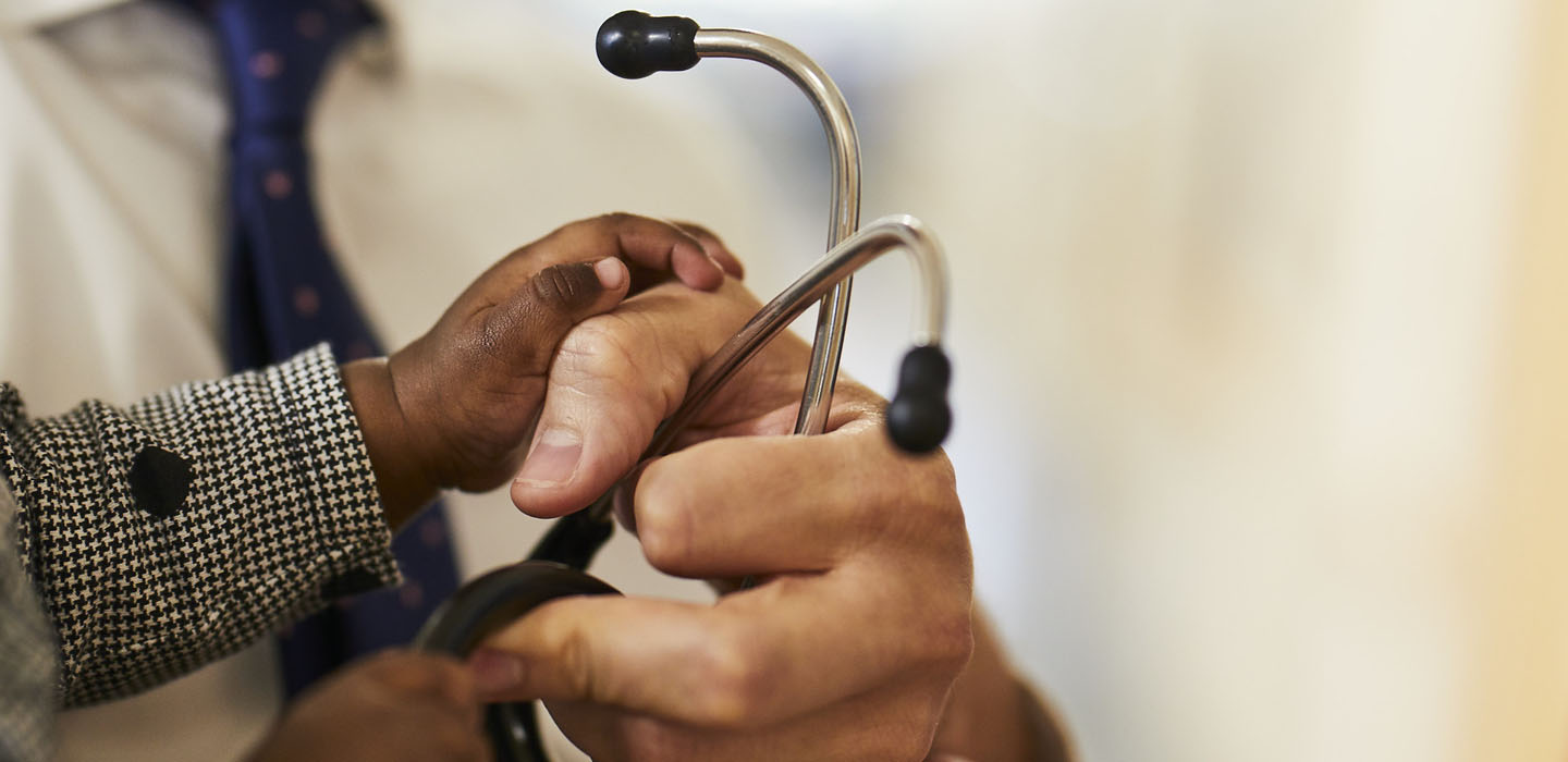 A doctor's and child's hands holding a stethoscope.