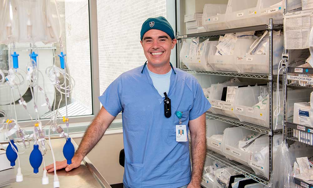Matt O'Brien in scrubs, smiling and posing in his lab.