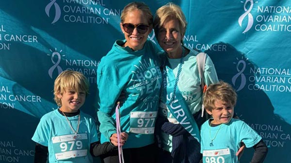 A group of individuals wearing teal shirts and ribbons participate in an outdoor event for the National Ovarian Cancer Coalition.
