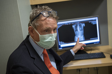 John T. Braun, MD, examines an x-ray of a patient's spine on a computer. 