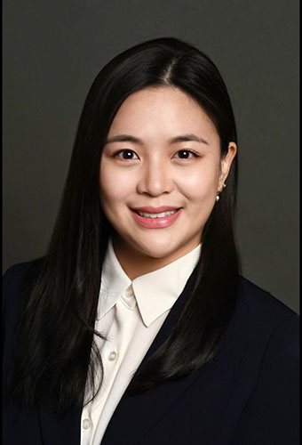 Headshot of Chelsey Lim in a black blazer and white shirt, sitting in front of a brown background