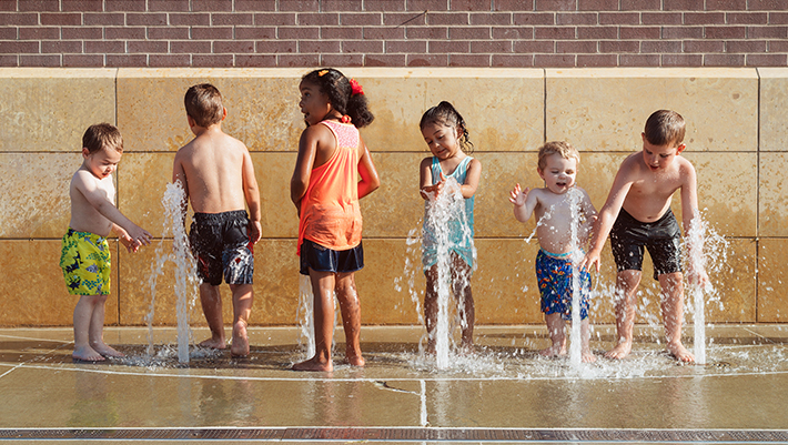 Photo of six school-age children playing in a fountain