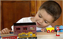 A little boy plays with a toy train set.