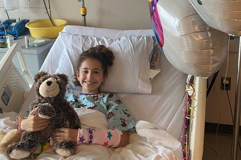 Lindsey Scheyer hugs a teddy bear in her hospital bed.