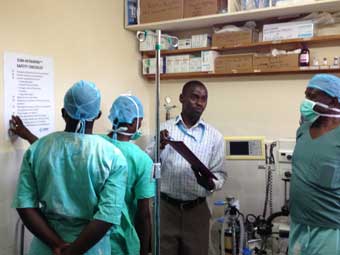 Three medical personnel listen to an instructor in the back room of a clinic.