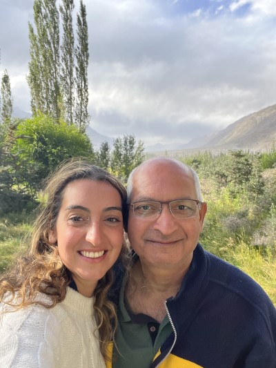 Dr. Singh and her father in India, with greenery and mountains behind them.