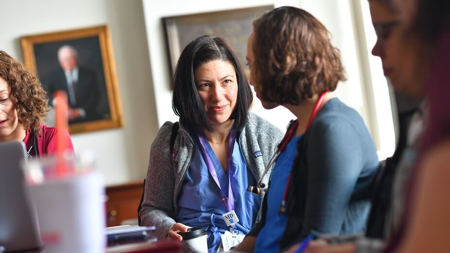 Staff members meet for interdisciplinary rounds at a table. 