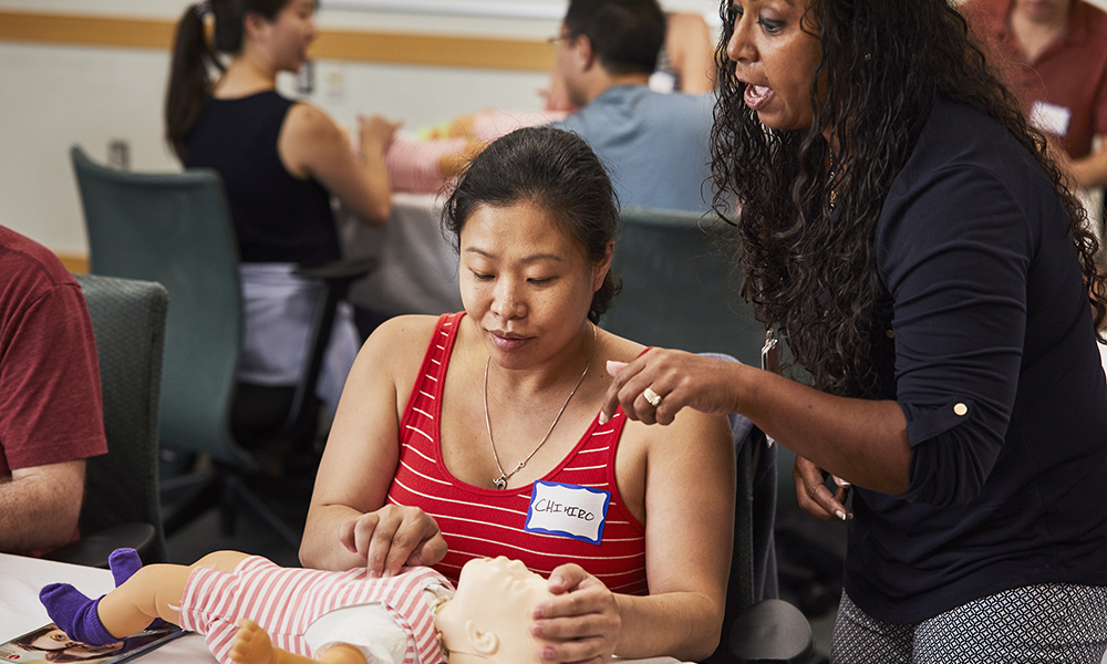 An instructor helps a participant with an instructional mannequin