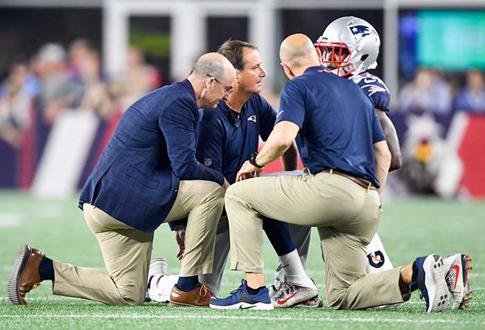 picture of three health care professionals on the field with a New England Patriots player