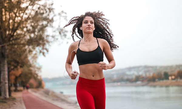 A fit young woman running on a lakeside path.