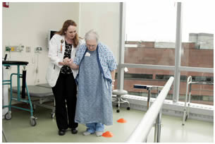 Image of physical therapist working with a patient using a walker. 