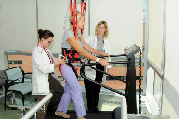 Physical therapists working with patient on treadmill.