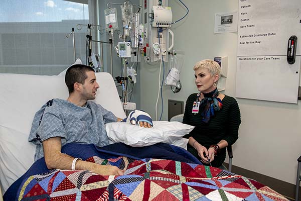 Social worker setting at a patient's bedside, having a conversation.