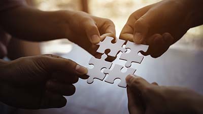 HAVEN Services - Two sets of hands putting puzzle pieces together. 
