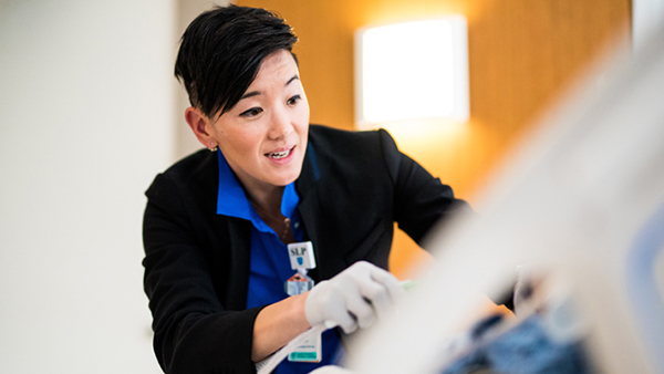 A smiling speech language pathologist smiling while speaking to a patient in bed.  A smiling speech language pathologist smiling while speaking to a patient in bed.