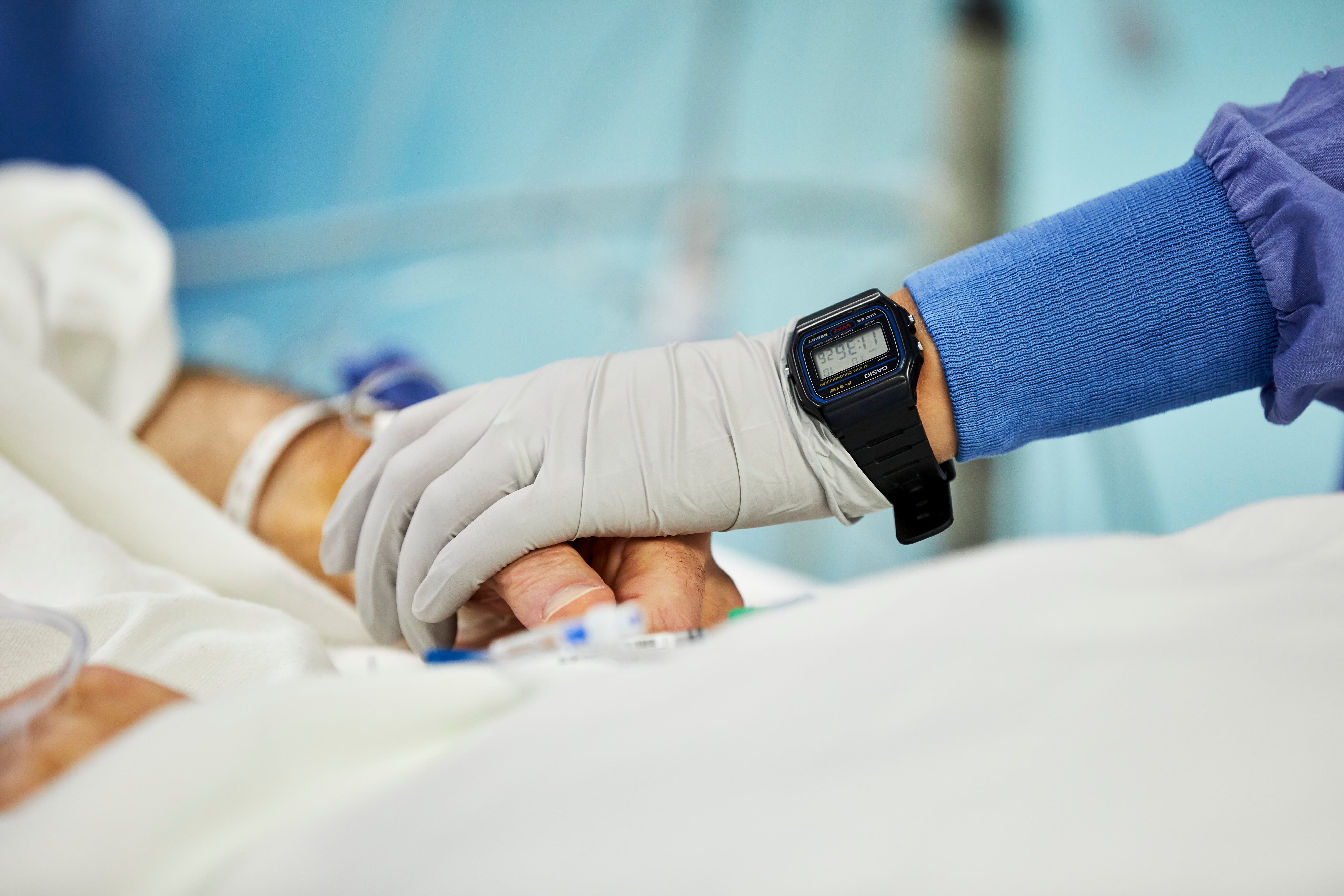 Provider touching the hand of a patient in a hospital bed
