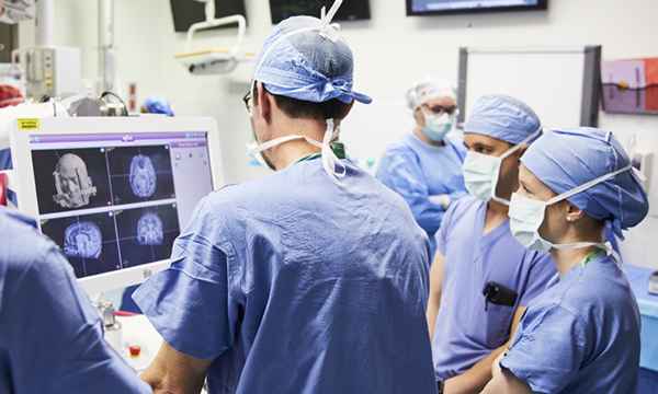 Physicians stand around a computer Physicians stand around a computer