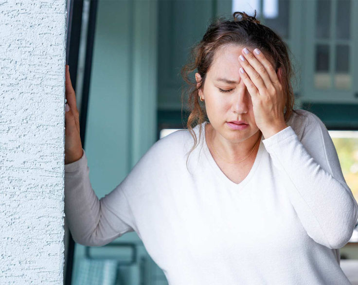 Woman with a hand on her forehead in pain