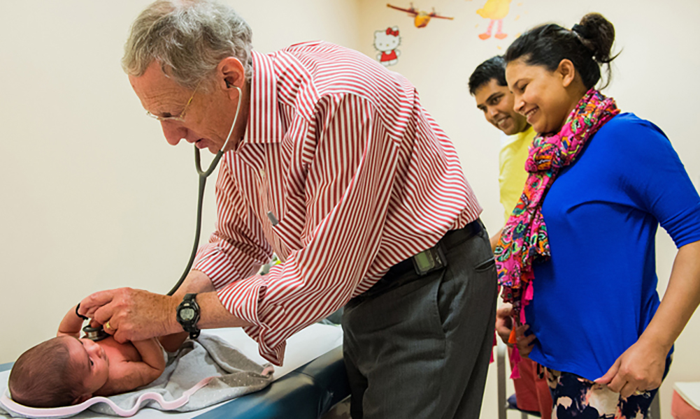 Photo of Peter Greenspan, MD, caring for a child with parents Photo of Peter Greenspan, MD, caring for a child with parents