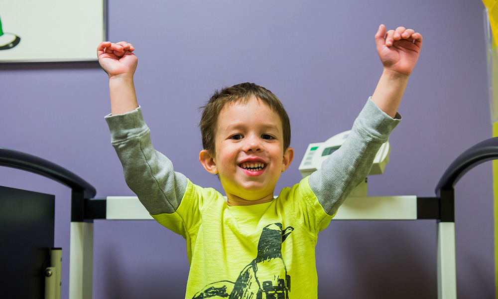 A brightly dressed small boy raises his arms in victory A brightly dressed small boy raises his arms in victory