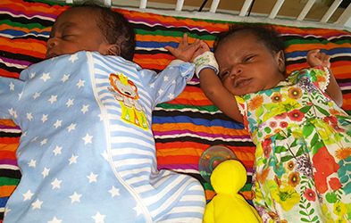 Mihaly and her brother sleeping in a crib.