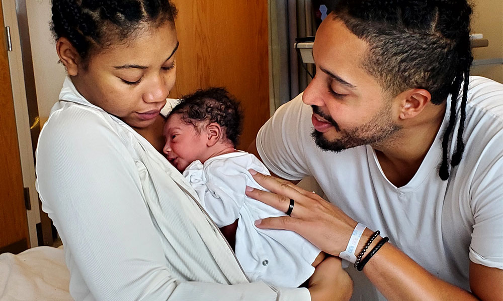 A mother and father hold their newborn baby. A mother and father hold their newborn baby.