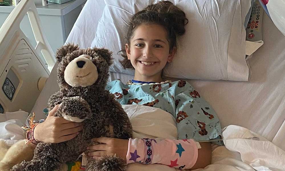 Lindsey Scheyer hugs a teddy bear in her hospital bed. Lindsey Scheyer hugs a teddy bear in her hospital bed.