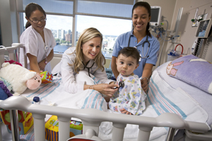 Image of Julie A. Piotrowski, RN, MSN, PNP-BC with baby and nursing students