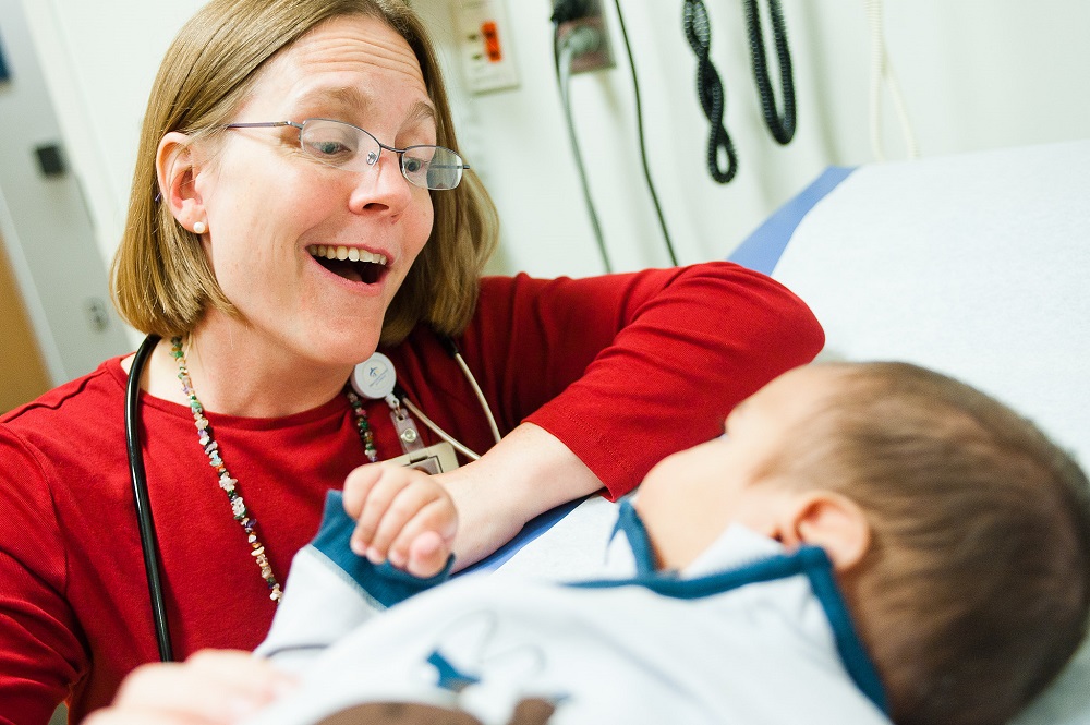 A smiling doctor makes a face at a baby. A smiling doctor makes a face at a baby.