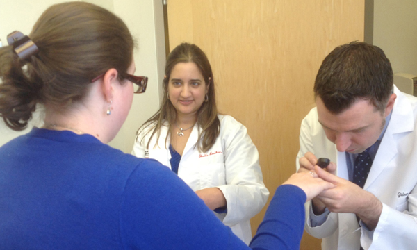 A specialist examines a woman's hand while another specialist looks on. A specialist examines a woman's hand while another specialist looks on.