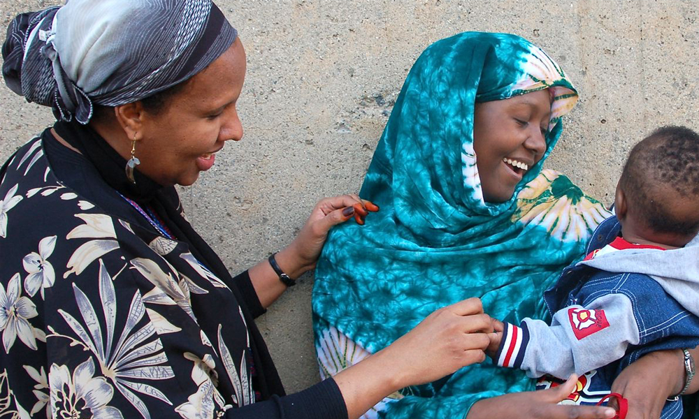 Two women smiling at a baby at a health clinic Two women smiling at a baby at a health clinic