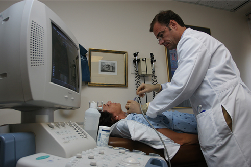 A doctor administers a treatment to a patient who lies on an examining table. A doctor administers a treatment to a patient who lies on an examining table.