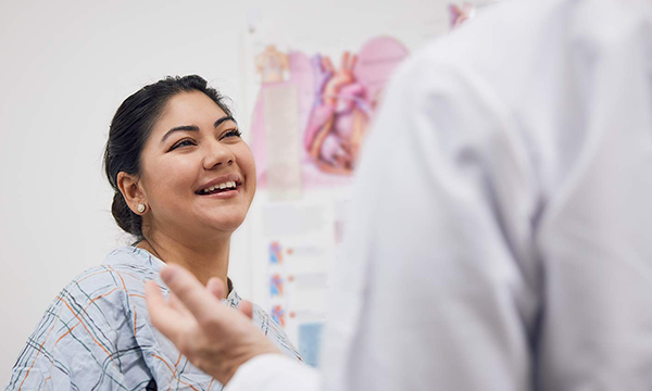 female patient smiling at doctor in exam room female patient smiling at doctor in exam room