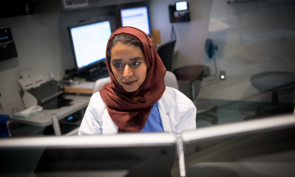 A white-coated practitioner consults a computer. A white-coated practitioner consults a computer.