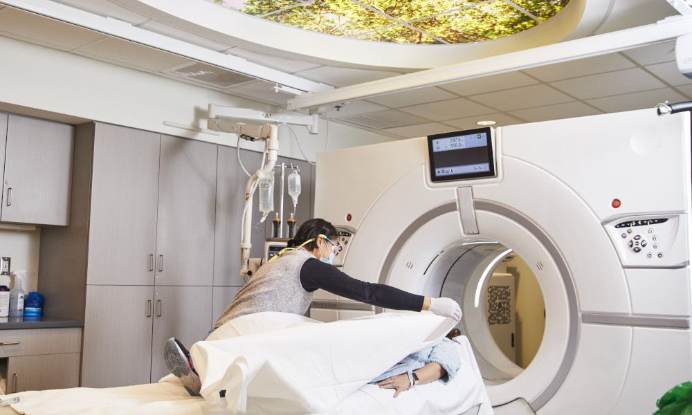 Radiologic technologist places blanket over patient on CT scanner Radiologic technologist places blanket over patient on CT scanner