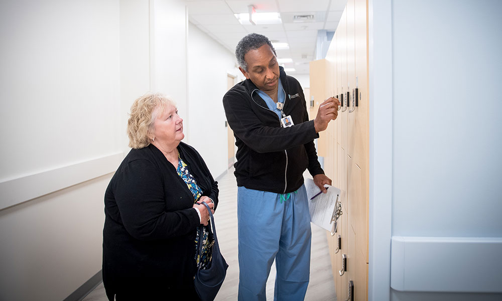 A technologist helps a patient with a locker