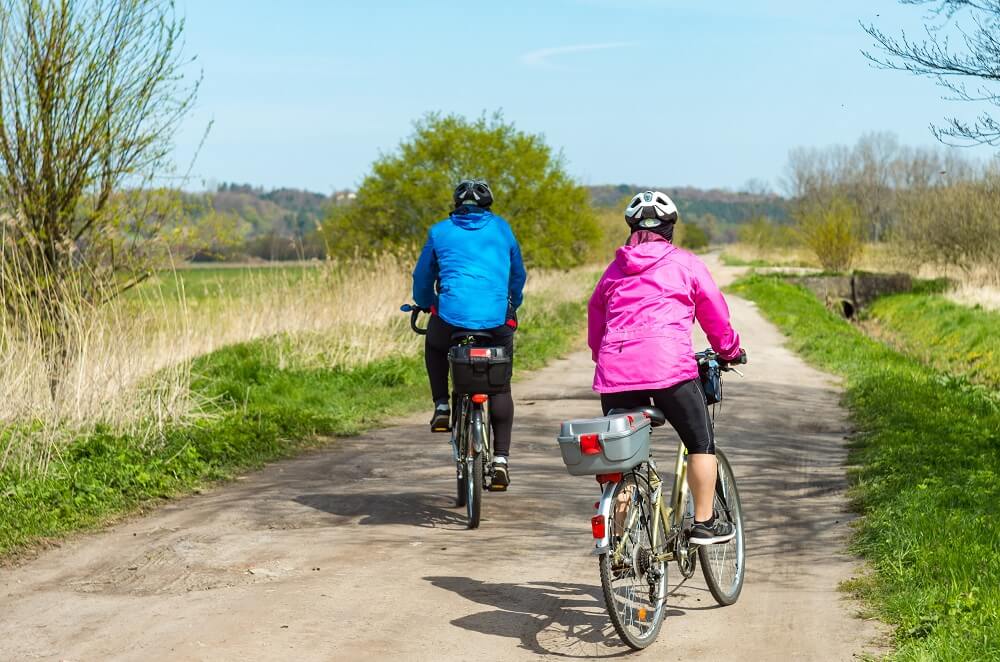Two bike riders ride down a country trail. Two bike riders ride down a country trail.