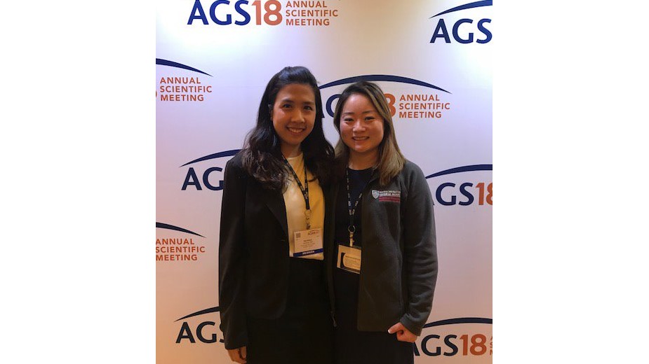 Two young women posing before a wall that reads, 'AGS18 Annual Scientific Meeting.' Two young women posing before a wall that reads, 'AGS18 Annual Scientific Meeting.'