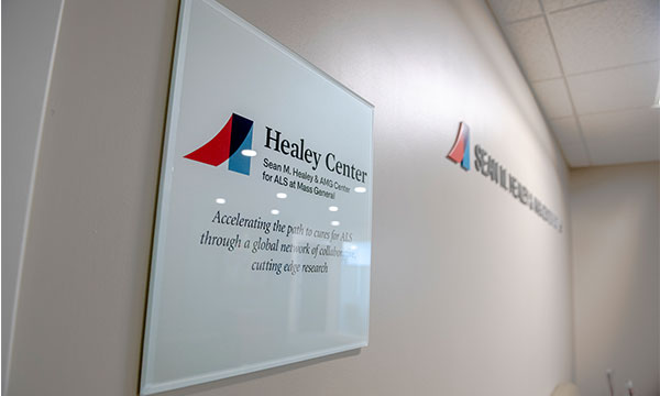 A sign at the Sean M. Healey & AMG Center for ALS at Mass General, displaying the center name and logo. A sign at the Sean M. Healey & AMG Center for ALS at Mass General, displaying the center name and logo.