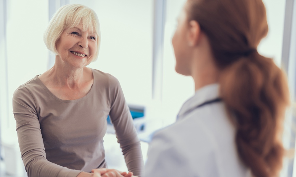 Silver-haired woman shaking hands with doctor in white coat Silver-haired woman shaking hands with doctor in white coat