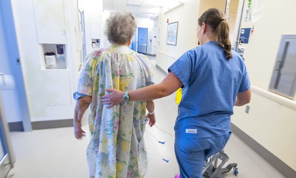 Helping a patient walk in the hospital hallway Helping a patient walk in the hospital hallway