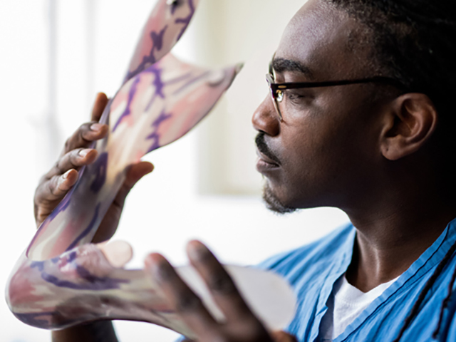 Orthotics tech examining a foot prosthetic very closely 