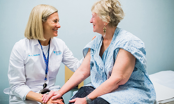 A white female practitioner and a white female patient consulting in an examination room. A white female practitioner and a white female patient consulting in an examination room.