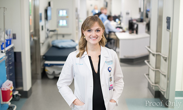 A young woman in a lab coat stands in a hospital hallway A young woman in a lab coat stands in a hospital hallway